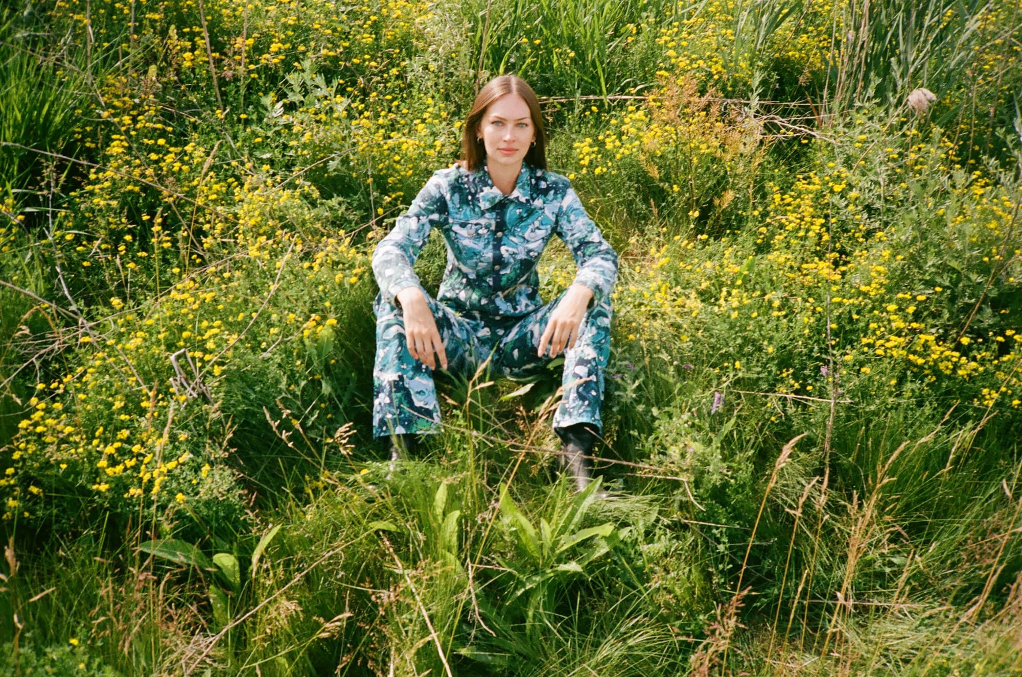 A model in a Jean Paul Gaultier printed set seated in a wildflower field